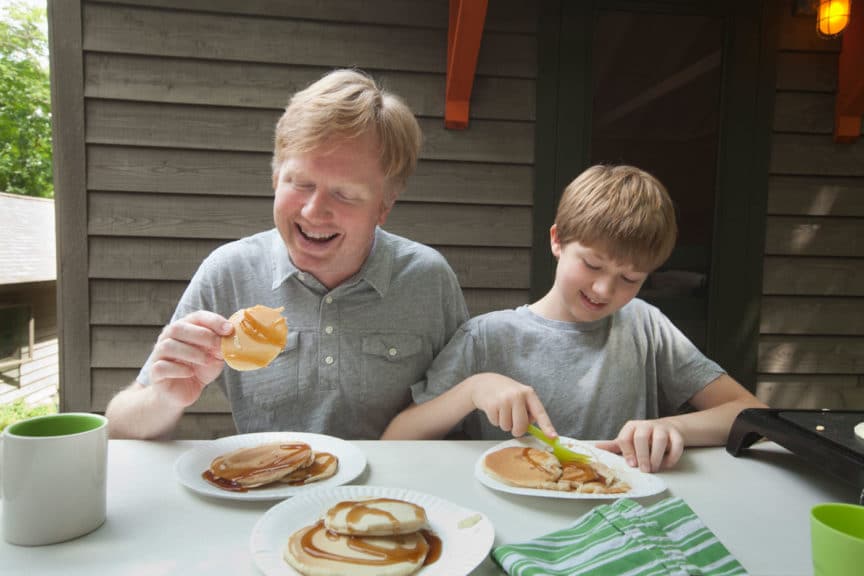 father and son eating pancakes outdoors