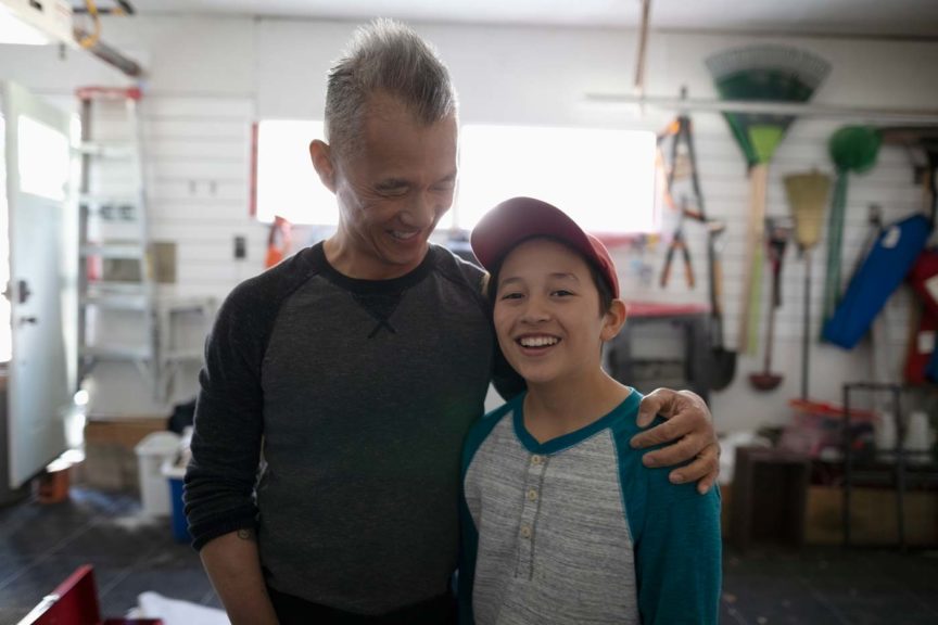 Father and son hugging smiling in garage