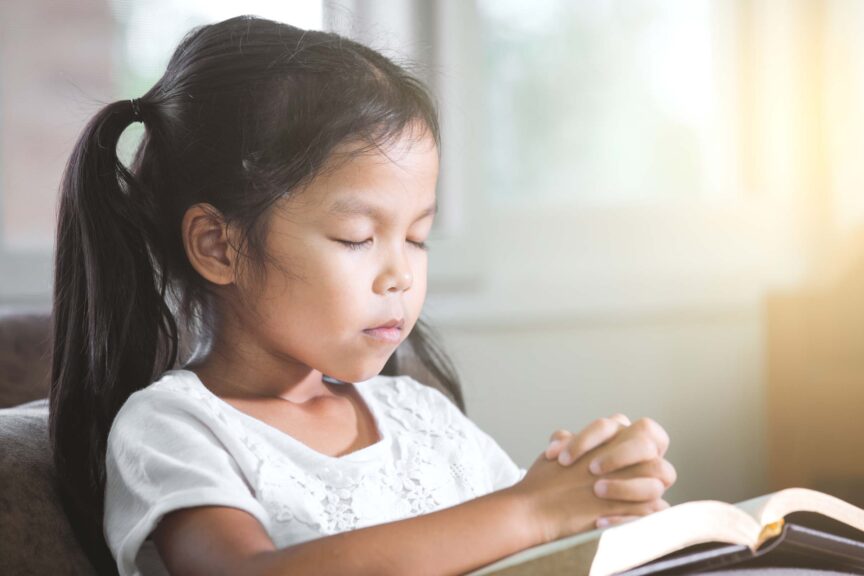 girl-closed-her-eyes-and-folded-her-hand-in-prayer-on-a-Holy-Bible