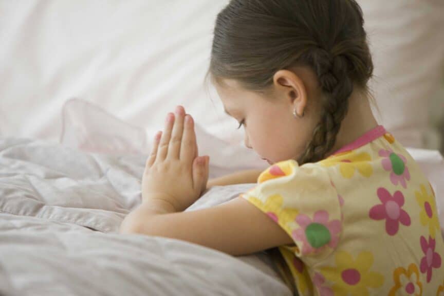 girl kneeling by bed praying