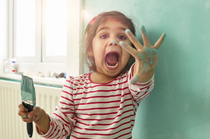 Girl playing around while painting her bedroom