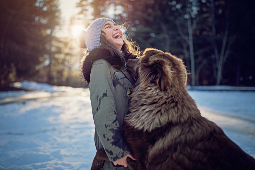 Little girl is playing with her dog in the snowy forest