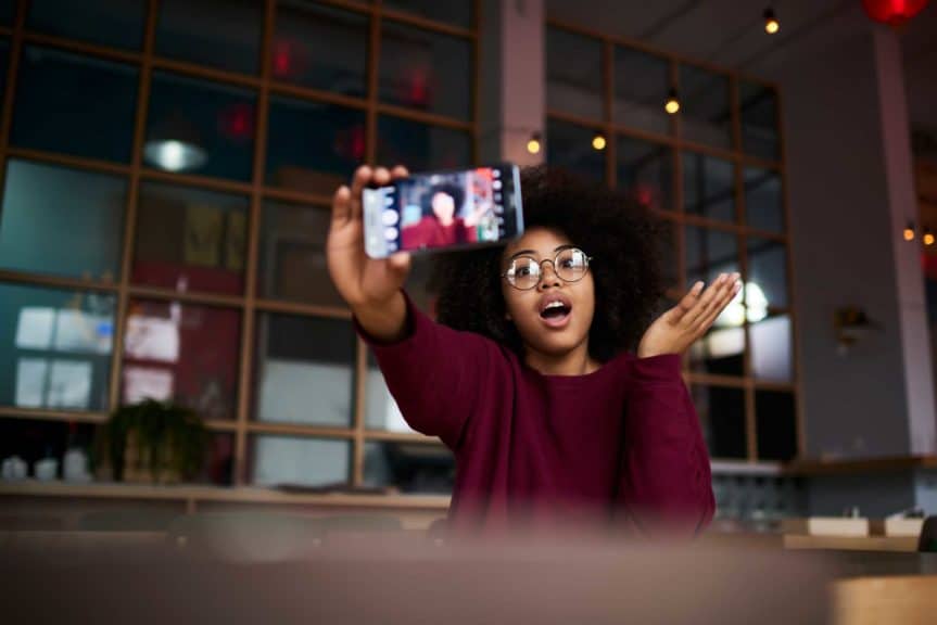 girl with curly hair in trendy glasses posing while making photo