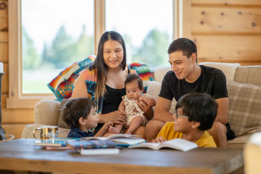 A family sits around a coffee table to do a Bible study together.