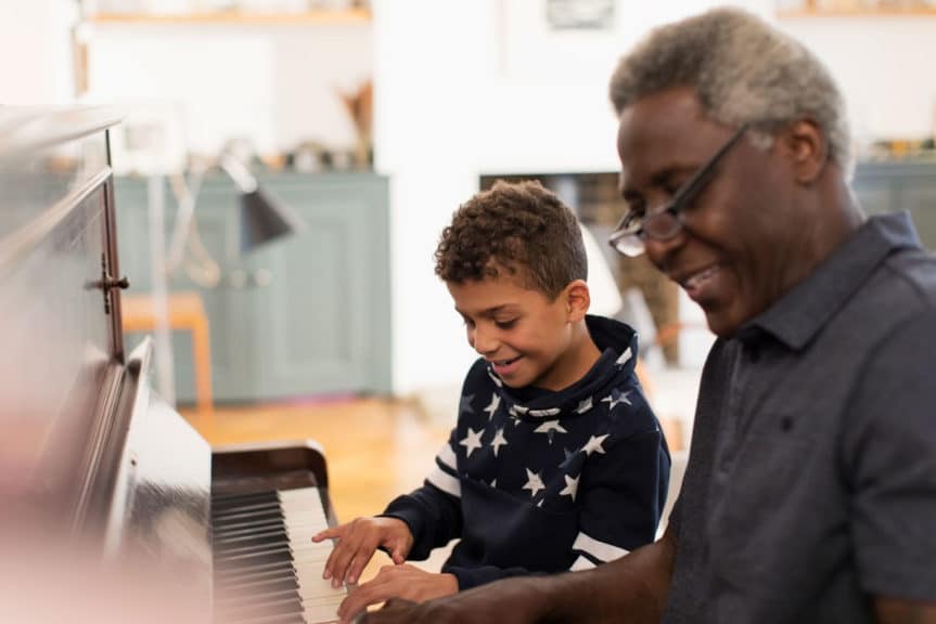 Grandfather and grandson cheerfully playing the piano