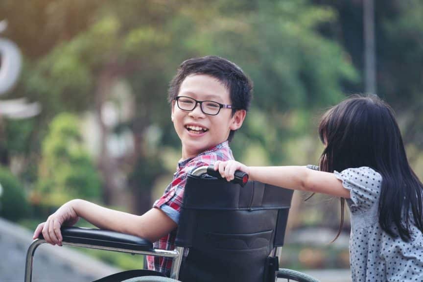 Boy in wheelchair smiling with sister