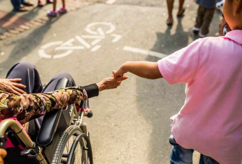 child holding hands with a woman in a wheelchair