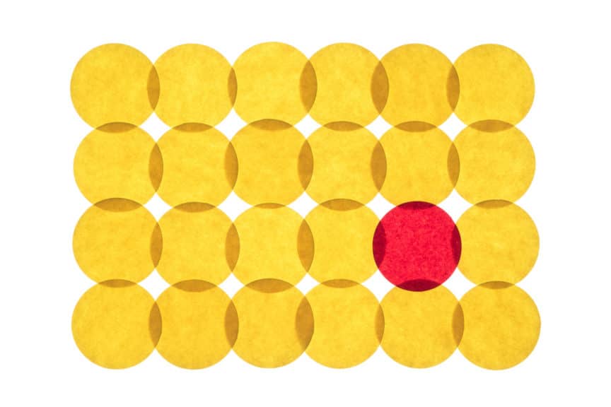 Interlocked yellow paper circles in rows and columns with one red one