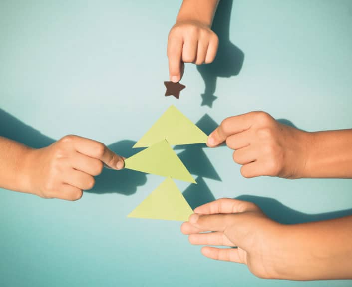 Kids hands holding paper cut out Christmas tree