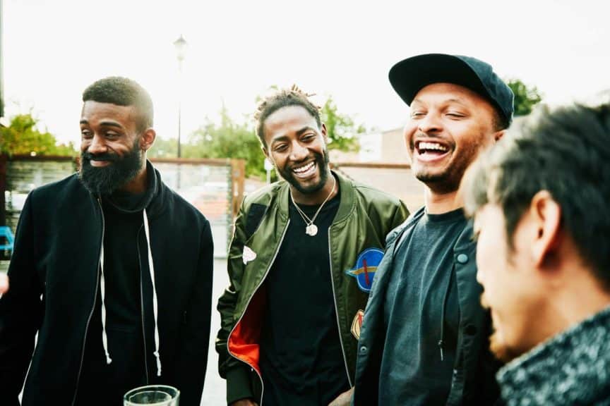 Laughing friends in discussion while hanging out at outdoor bar