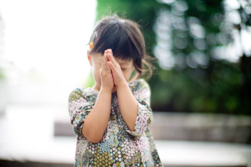 Little girl praying with hands together