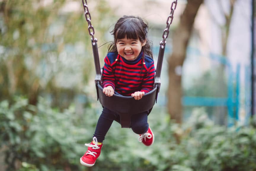 Little girl swinging on the swing joyfully