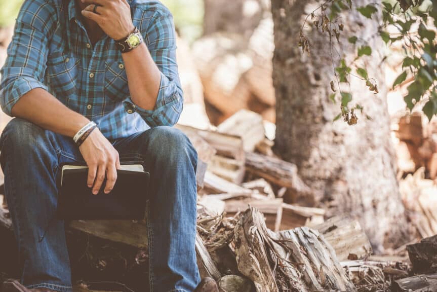 man-bible-sitting-outdoors-log