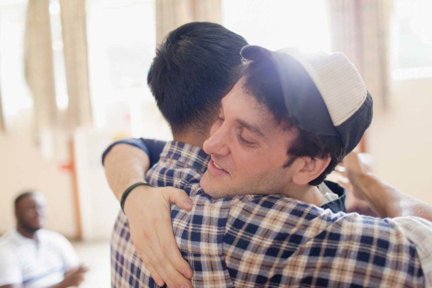 Man in hat hugging man