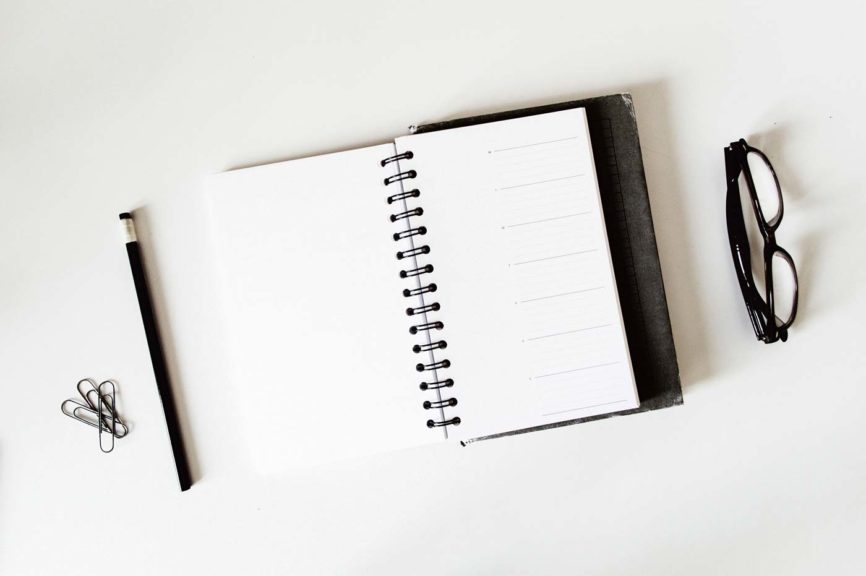 Planner, pencil, reading glasses on a table