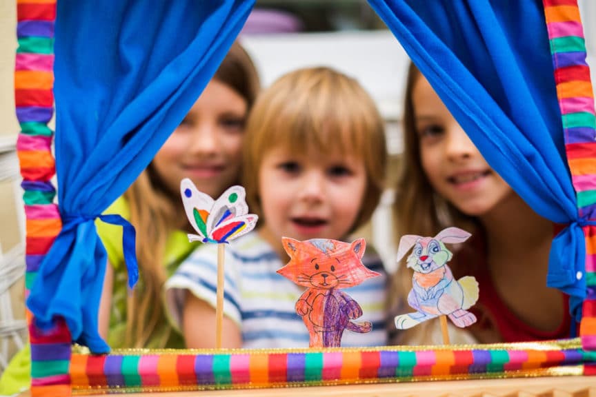 Portrait three cute children playing puppet show