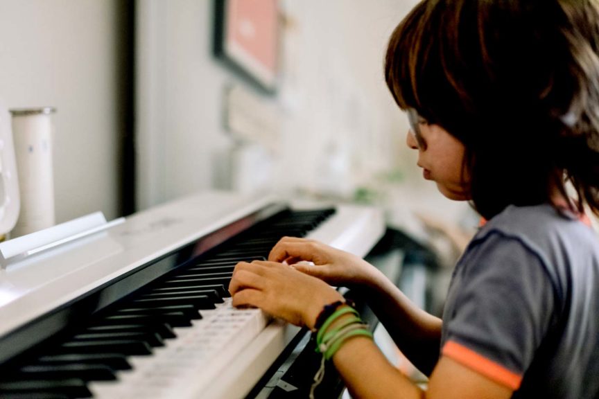 Side view of child playing on a smart piano