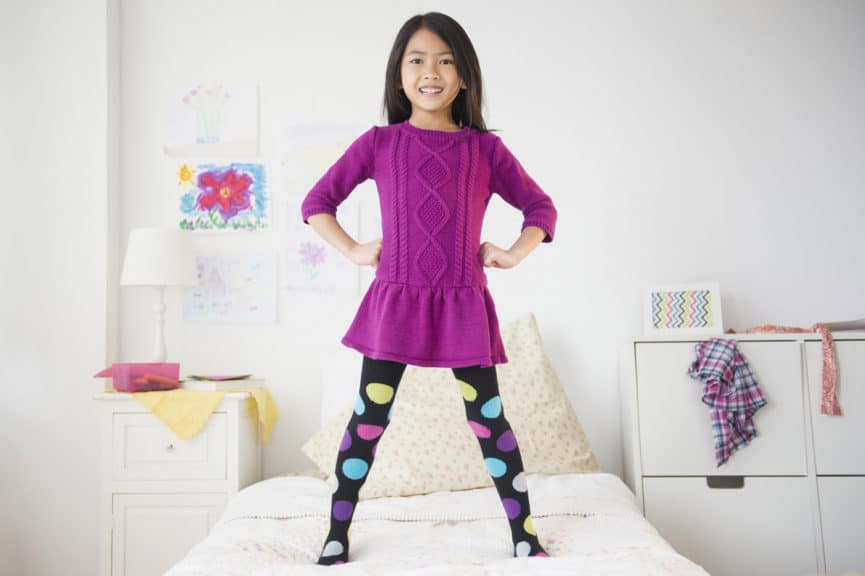 Smiling girl standing on bed