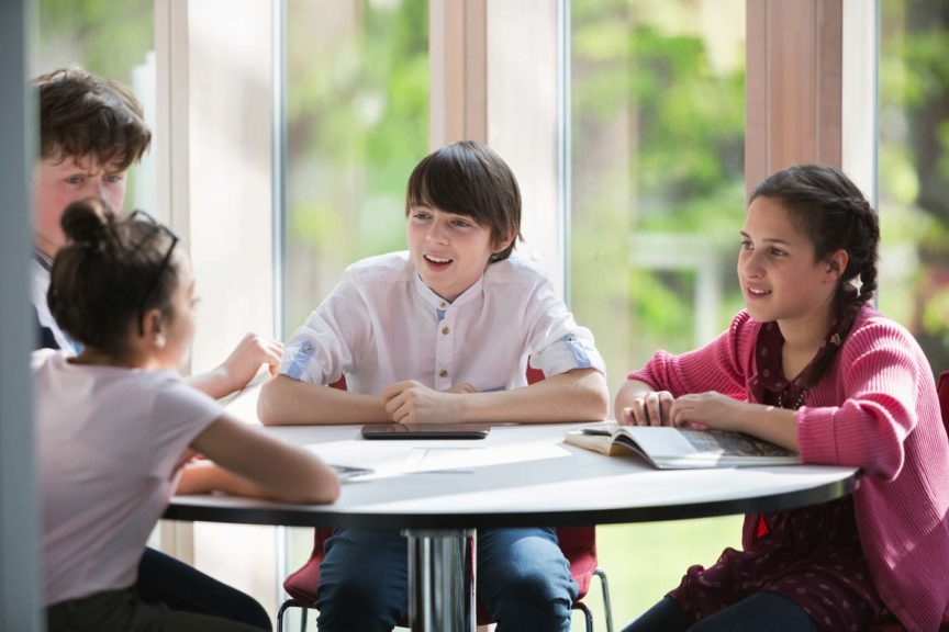 Students talking at table in library