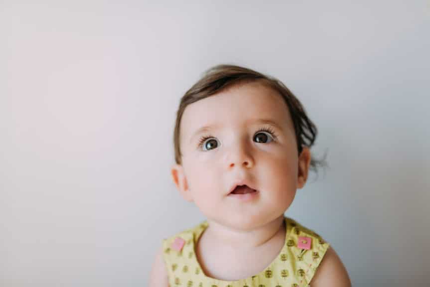 Surprised baby girl looking up on white background
