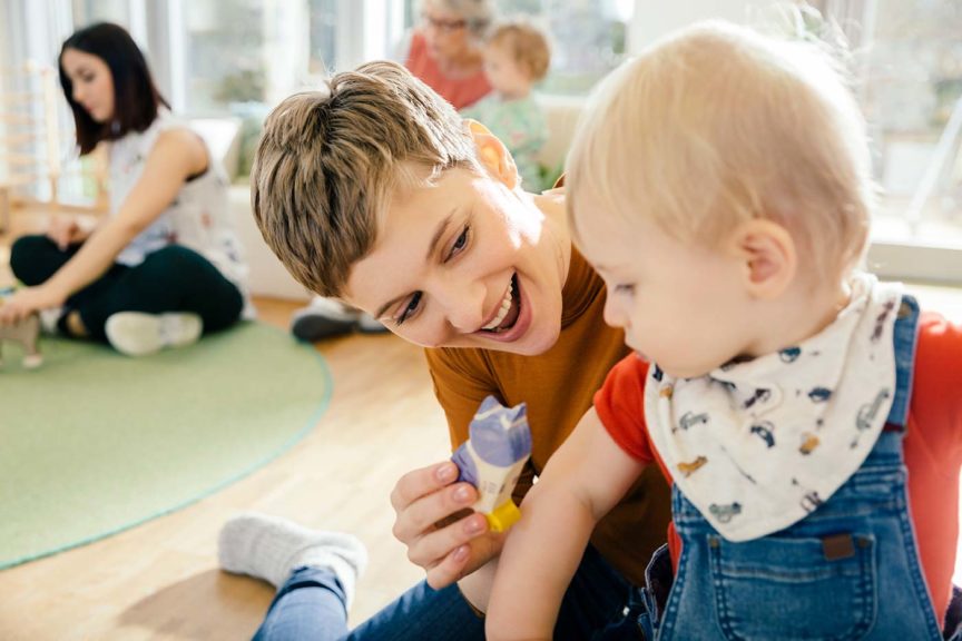 teacher playing with toddler ministry volunteers