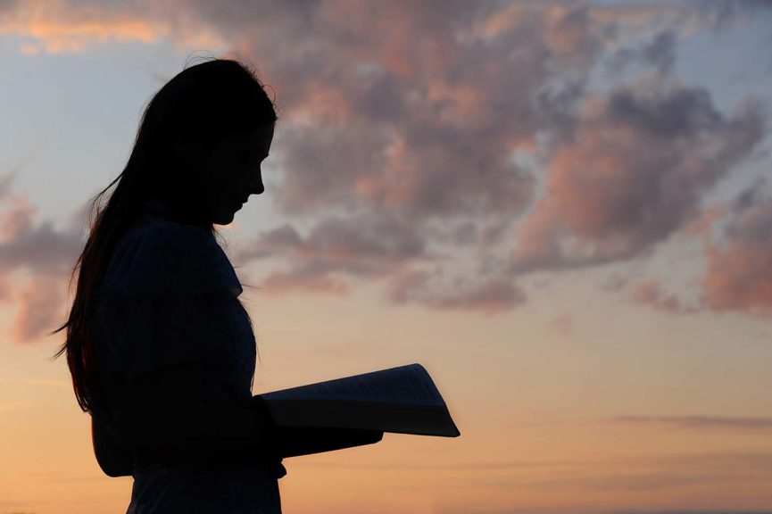 teenage girl with Bible at sunset