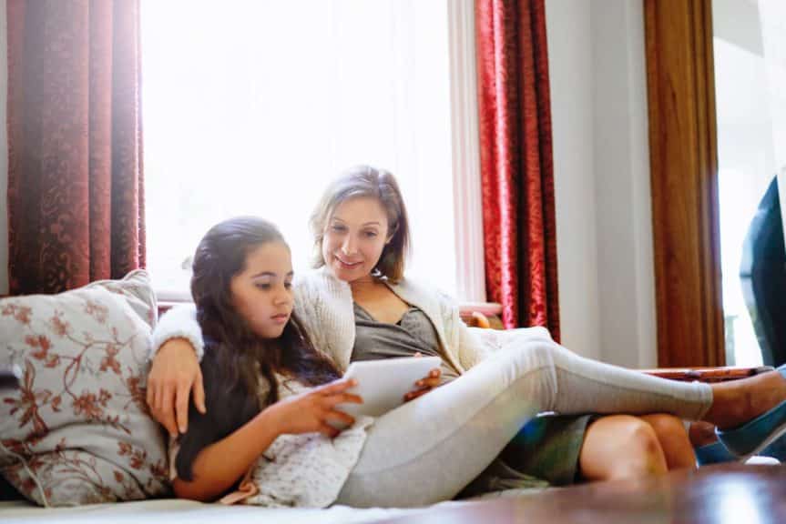 eenager using tablet while resting with mother