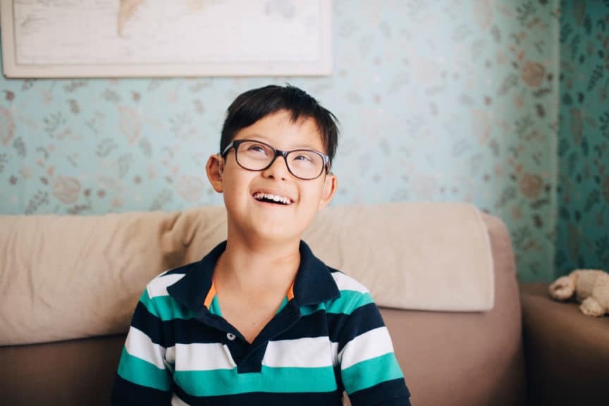 Thoughtful boy laughing while sitting on sofa at home