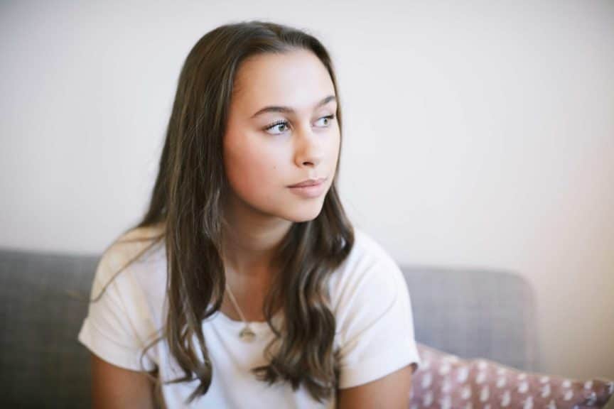 Thoughtful teenage girl sitting at wellness center