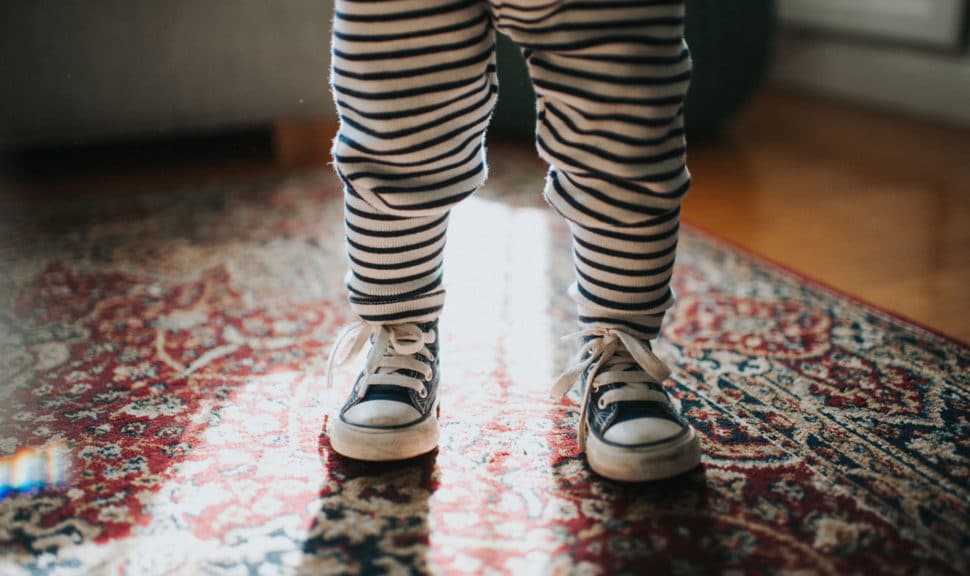 Toddler wearing sneakers standing on carpet