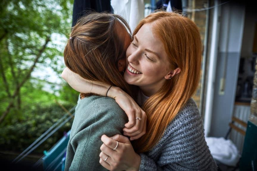 Two young friends embracing on the balcony