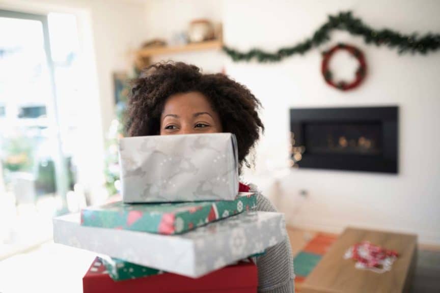 Portrait woman carrying stack of Christmas gifts