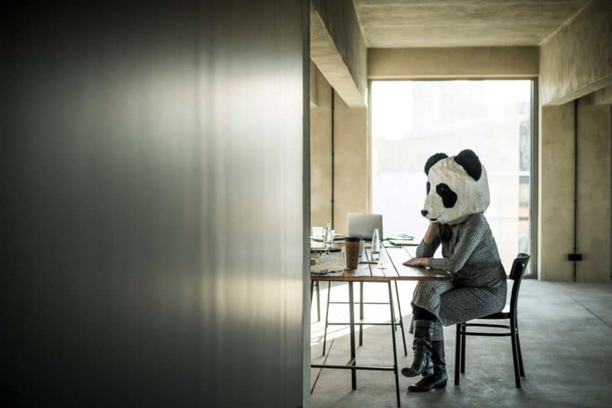 Woman with panda mask sitting in office, thinking