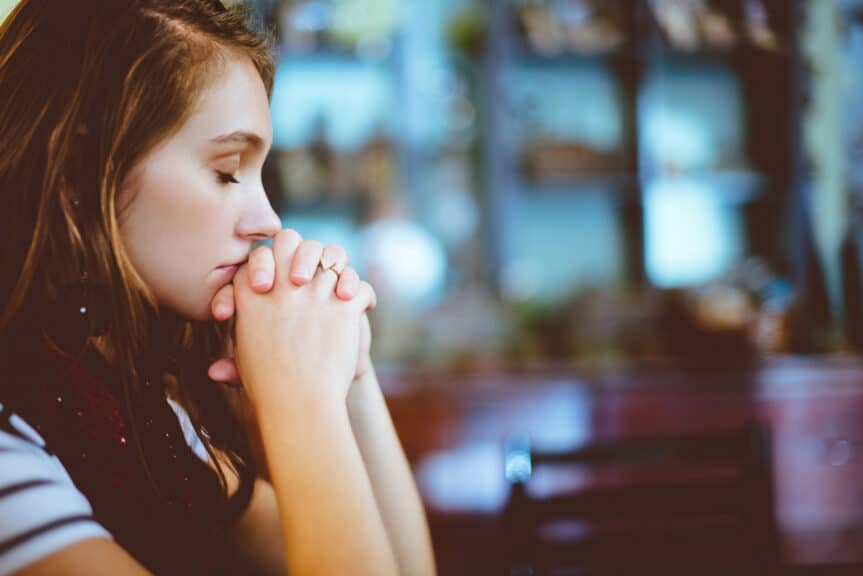 woman-praying-sitting-table