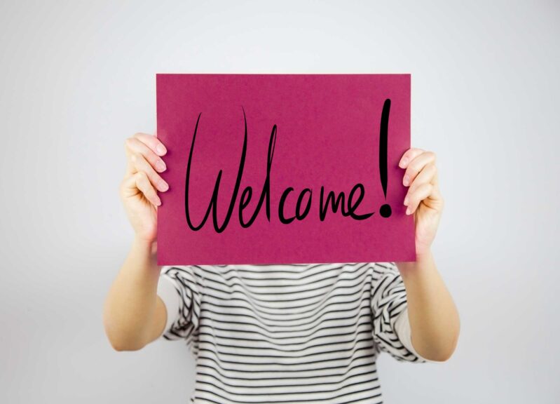 Woman showing a paper page saying WELCOME