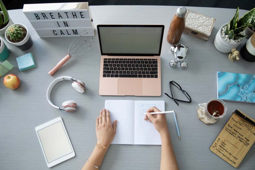 Woman writing at desk and pink computer