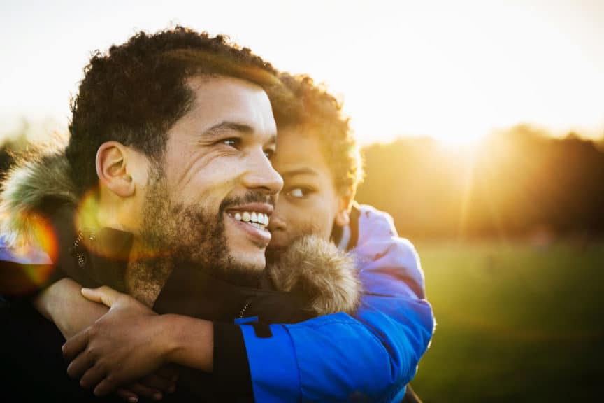 Young Boy Holding Onto His Dad At The Park 