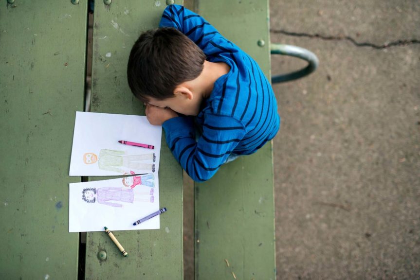 oung boy looking sad at drawing of a broken family